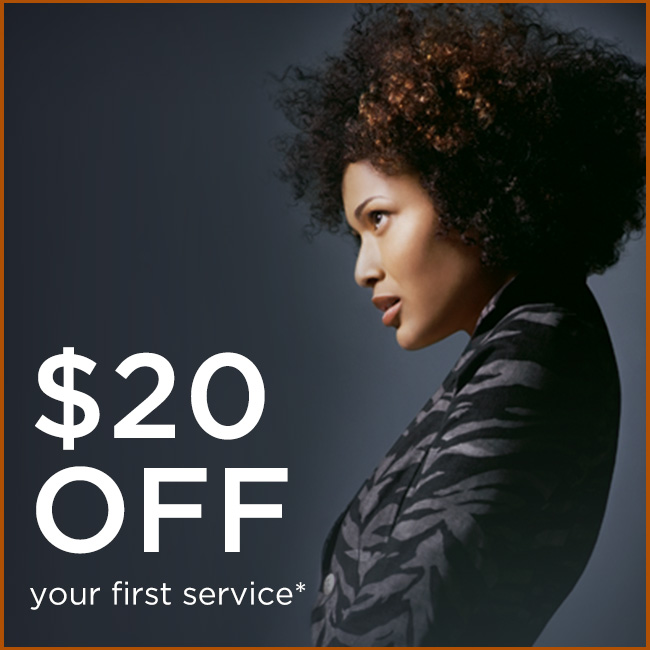A woman with curly hair in a patterned jacket faces sideways; text reads "$20 OFF your first service*". - Elixir Salon | Berkeley, CA